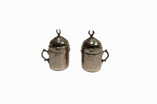 A pair of coffee cups encased in beaten silver metal