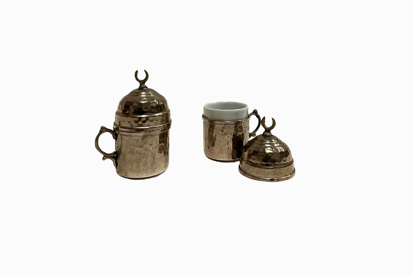 A pair of coffee cups encased in beaten silver metal