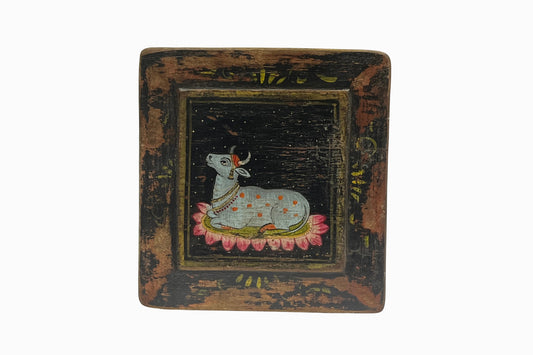 A black painted panel picture of a holy cow.